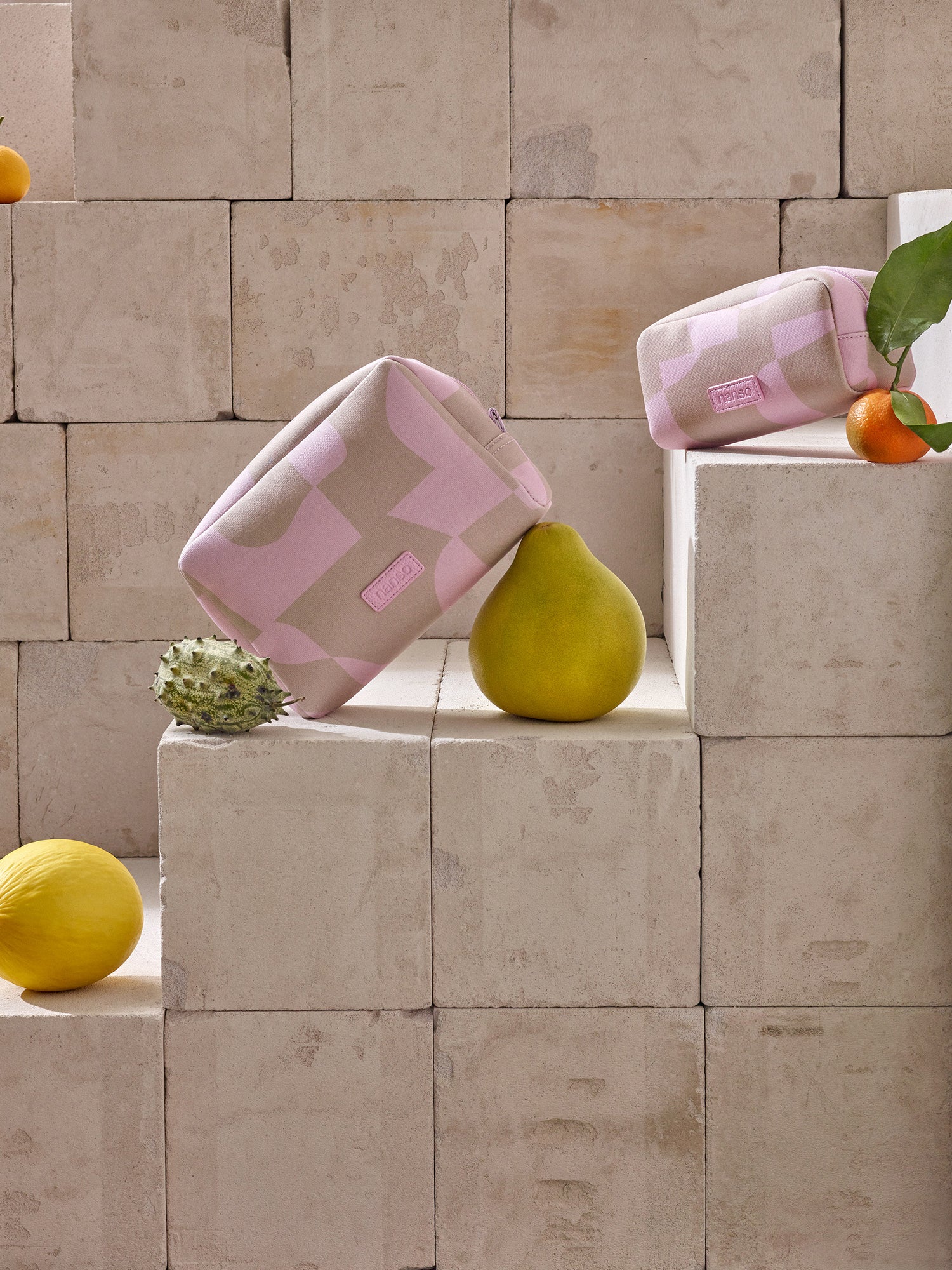 Nanson Kallio -kosmetiikkalaukut kauniissa asetelmassa hedelmien kanssa.