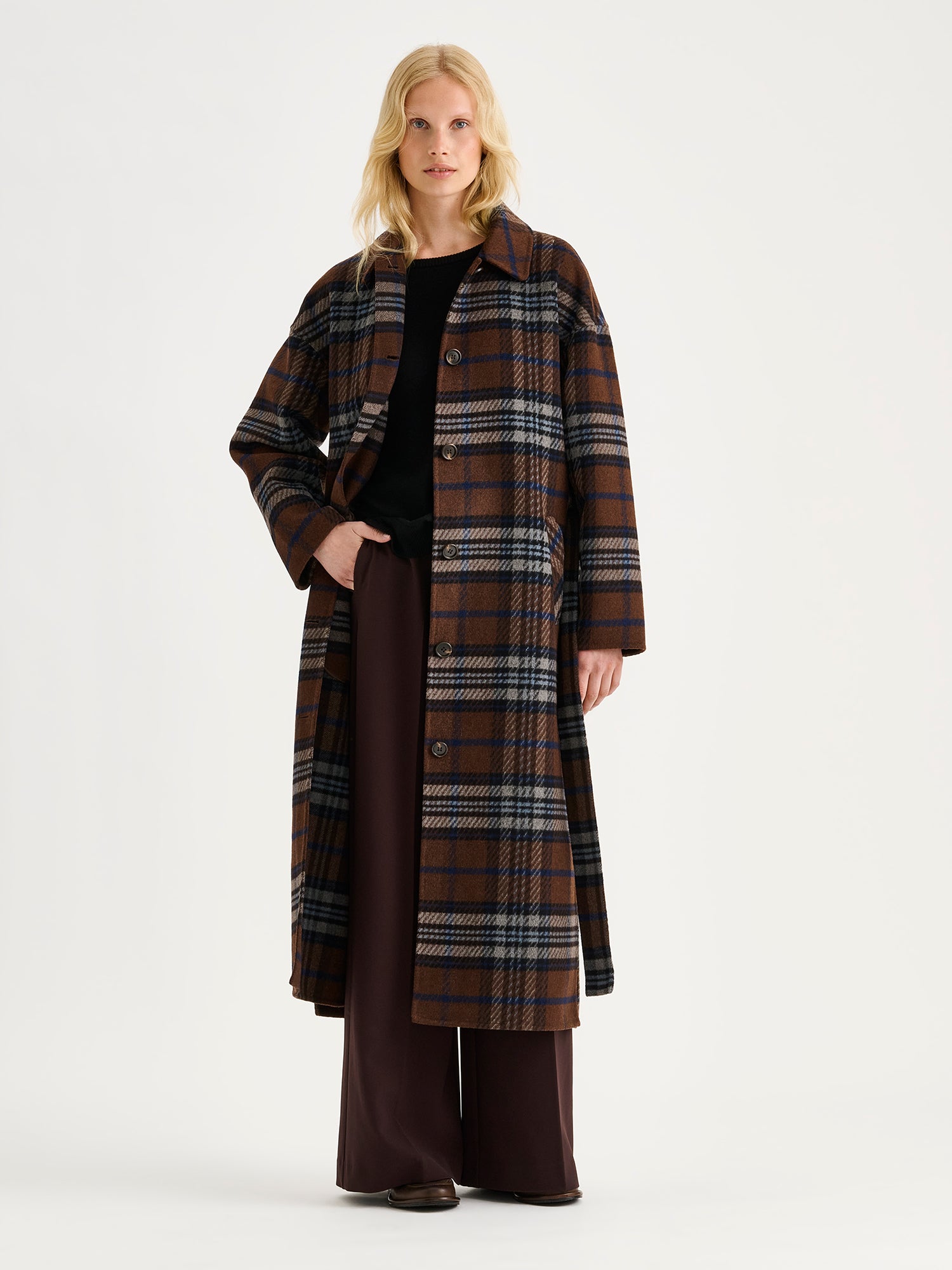 Tyylikäs ja klassinen Astrid-villakangastakki trendikkäällä ruutukuosilla, mallin päällä farkkujen kanssa.