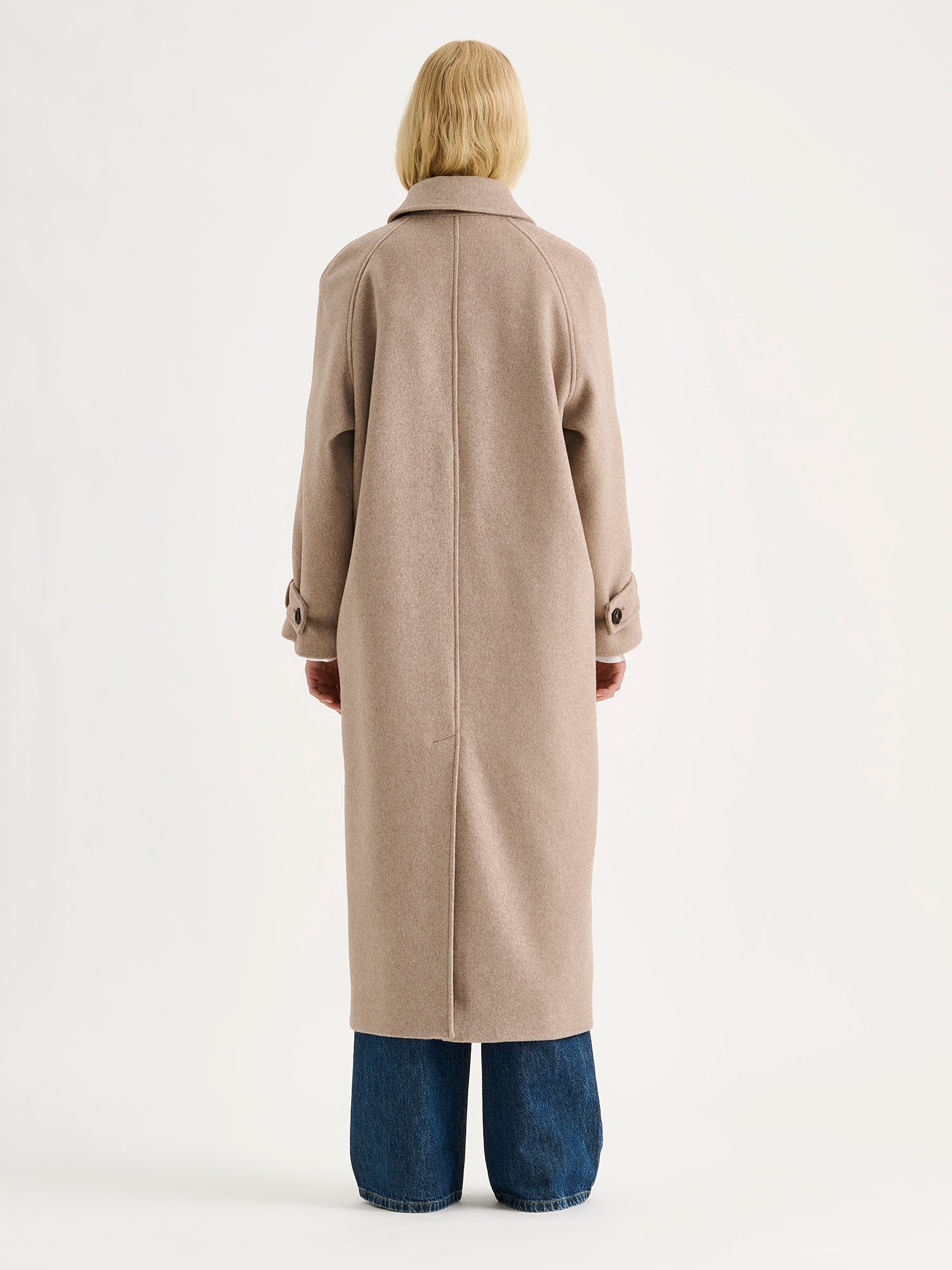 Nanson ajattoman tyylikäs ja klassinen beige Tove pitkä villakangastakki mallin päällä sinisten farkkujen kanssa, kuva takaa.