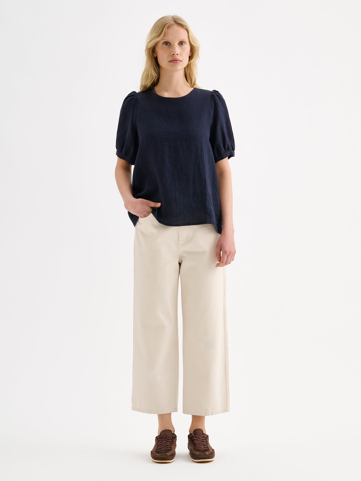 Nanson naisten kaunis tummansininen Sarastus-pellavapusero lyhyillä puhvihihoilla mallin päällä vaaleiden farkkujen kanssa.