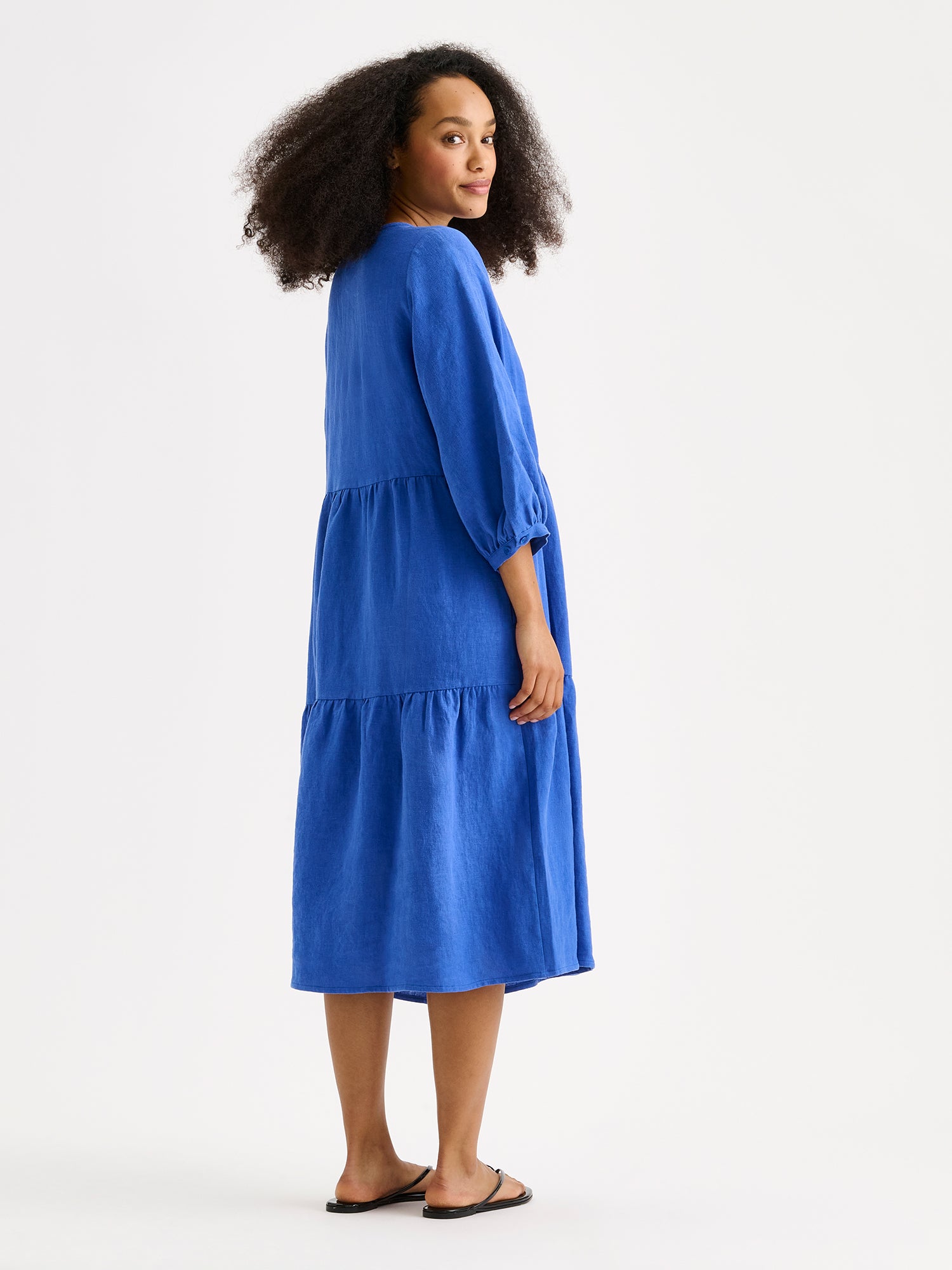 Nanson sininen midipituinen frillahelmainen Saralivia pellavamekko, jossa on kauniit 3/4 hihat, sivutaskut ja V-pääntie. Pellavamekon istuvuus on väljä ja materiaali on hengittävä. Kuvassa mallin päällä takaa kuvattuna.