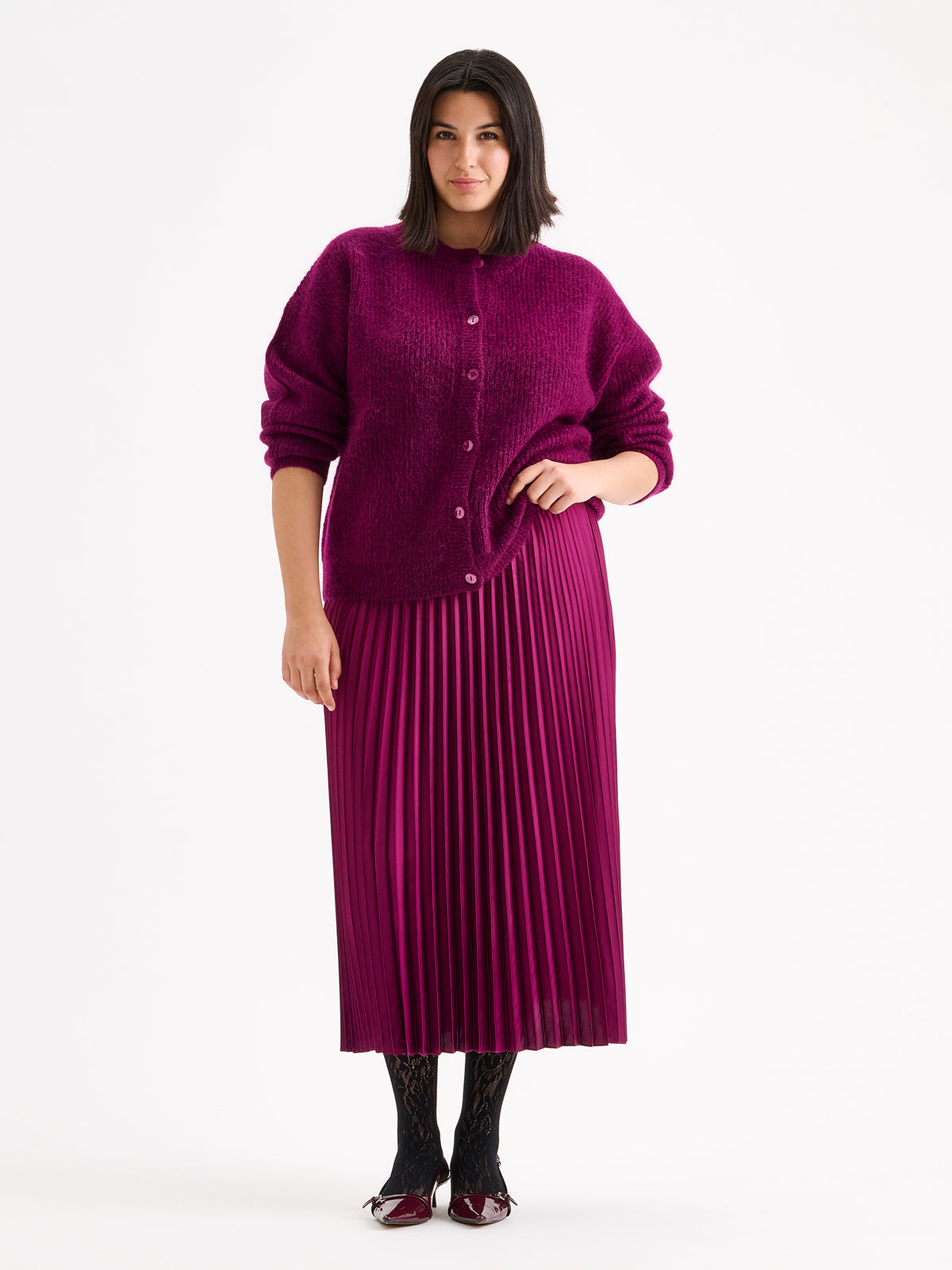 Nanson naisten ihanan lämmin Sumi-neuletakki hurmaa hehkuvalla violetin sävyllään ja muhkean pörröisellä pinnallaan. Mallin päällä violetin pliseeratun hameen kanssa.