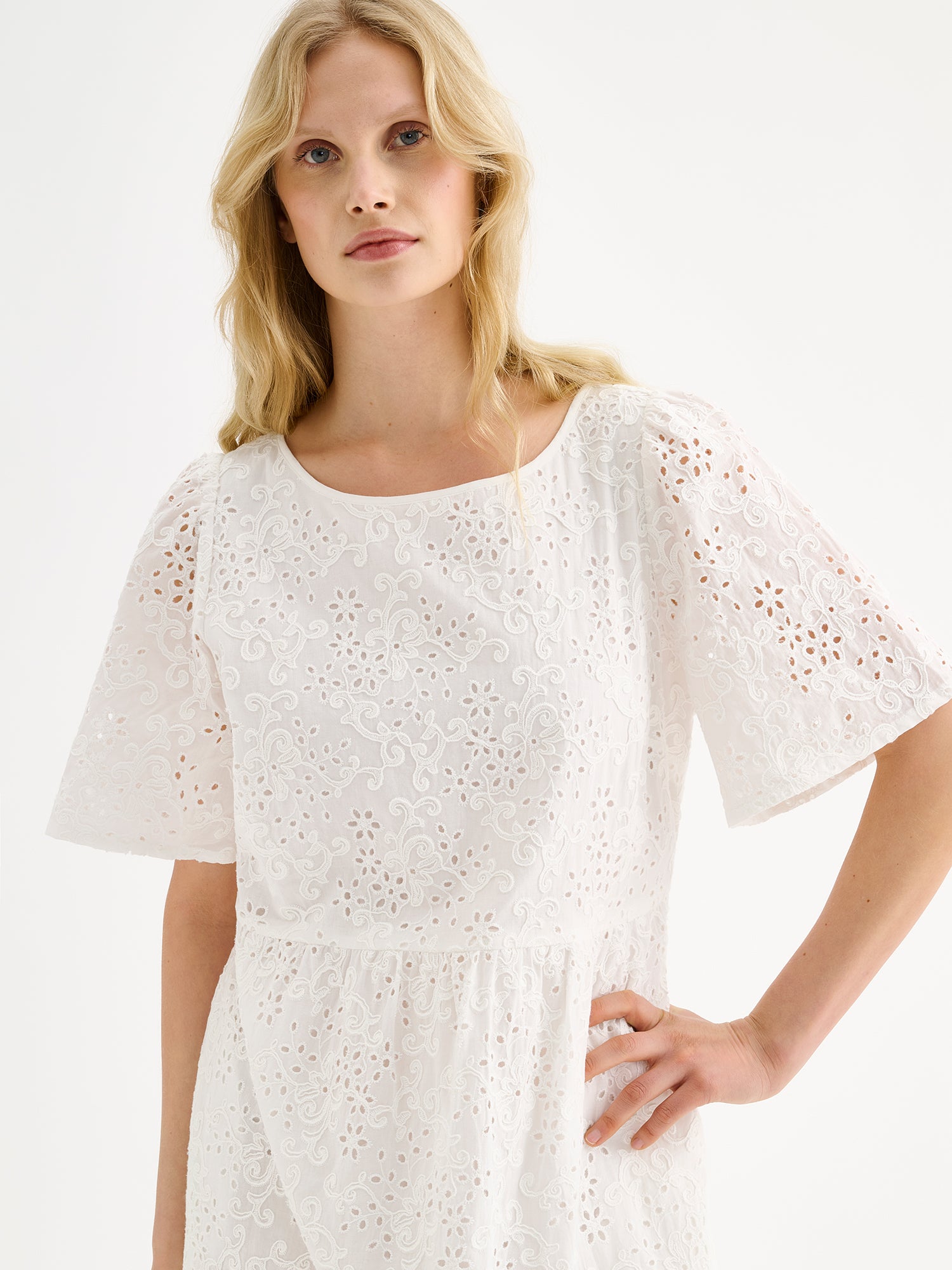 Nanson naisten kaunis pitkä luonnonvalkoinen Odette-mekko pitsimäisestä Broderie anglaise -tyyppisestä puuvillakankaasta mallin päällä lähikuvassa.