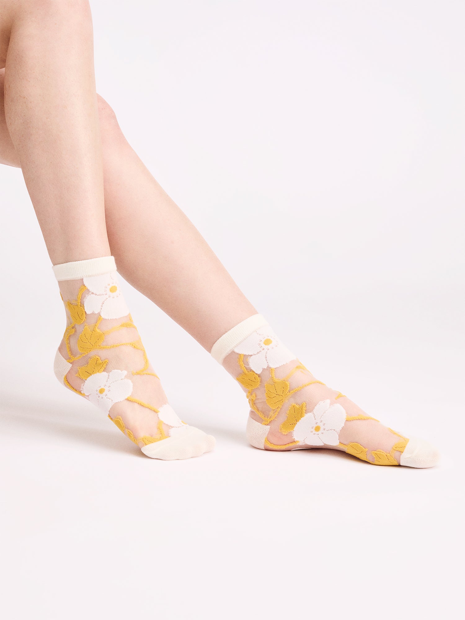 Voguen trendikkäät kukkakuosilliset läpikuultavat sukat herkällä värityksellä. Näillä sukilla kruunaat asusi ja tuot siihen kauniin yksityiskohdan. Tuotekuva mallin jalassa.