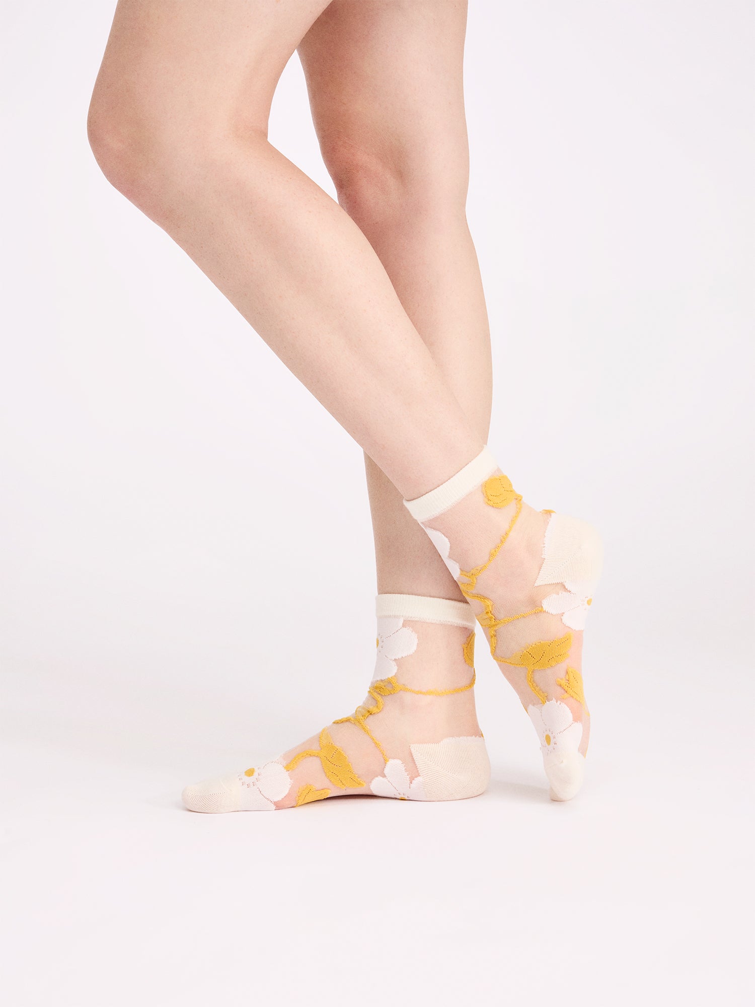 Voguen trendikkäät kukkakuosilliset läpikuultavat sukat herkällä värityksellä. Näillä sukilla kruunaat asusi ja tuot siihen kauniin yksityiskohdan. Tuotekuva mallin jaloissa.