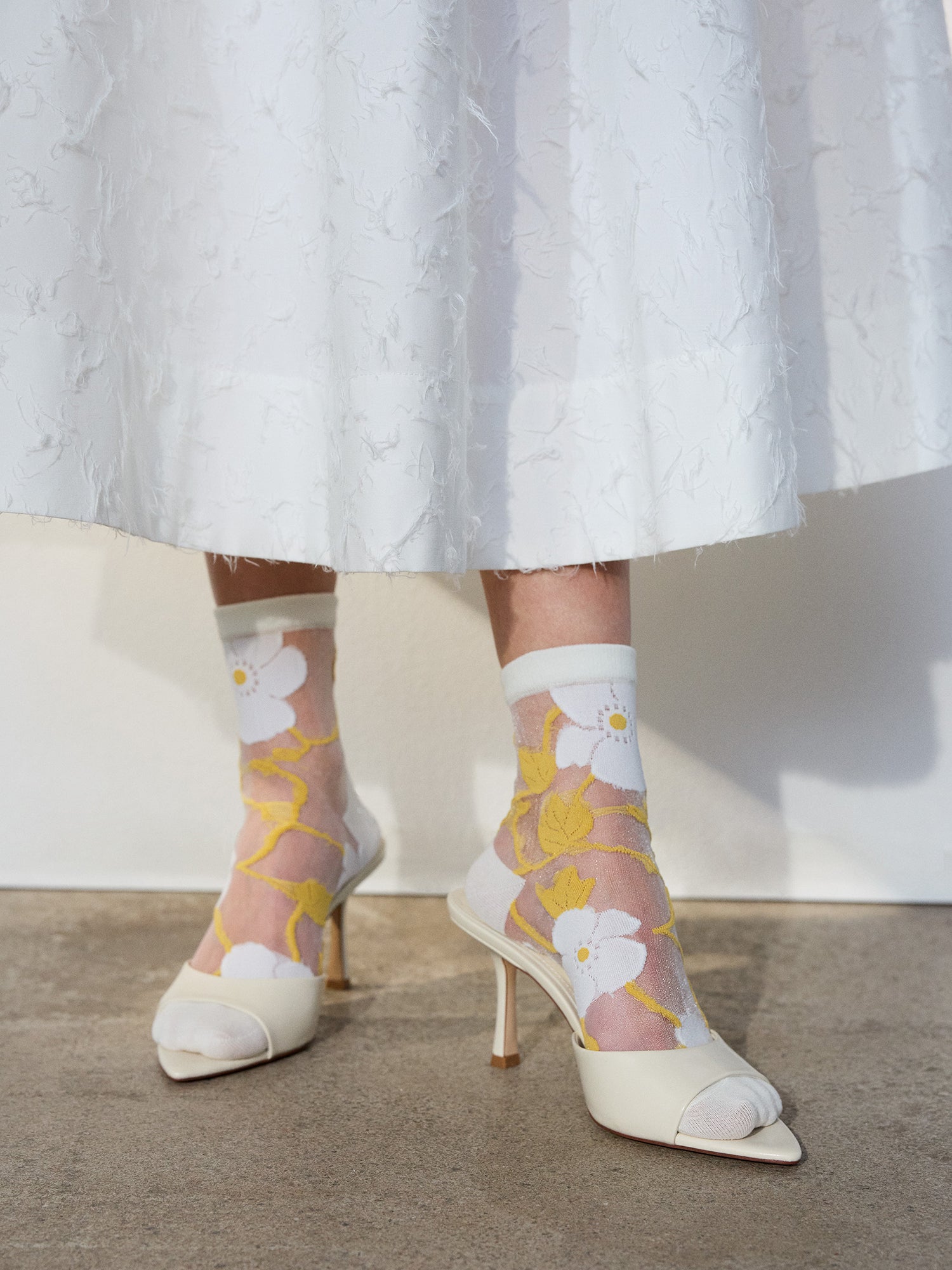 Voguen trendikkäät kukkakuosilliset läpikuultavat sukat herkällä värityksellä. Näillä sukilla kruunaat asusi ja tuot siihen kauniin yksityiskohdan. Kuva sukista mallin yllä.