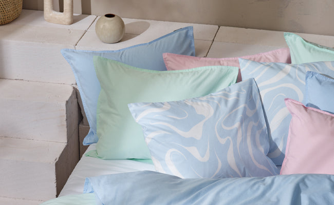 Nanson pastellisävyiset tyynyliinat kauniissa asetelmassa.