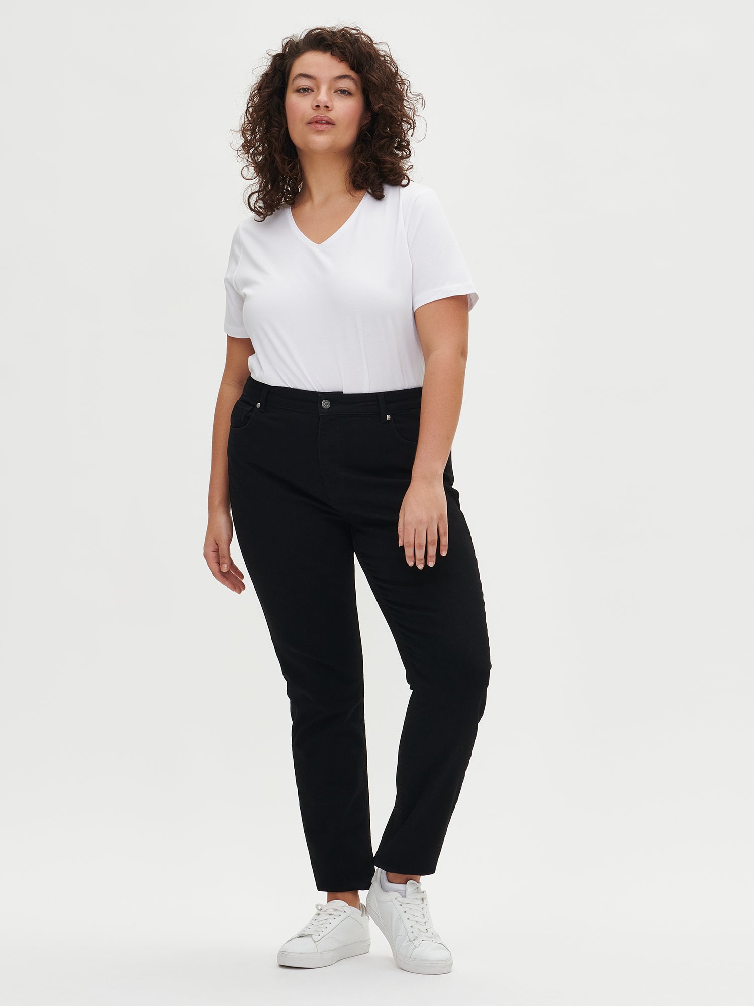 Nanson naisten istuvat mustat Pilli-farkut edestä plus size -mallilla. Mallilla yllä Nanson valkoinen V-pääntien T-paita.