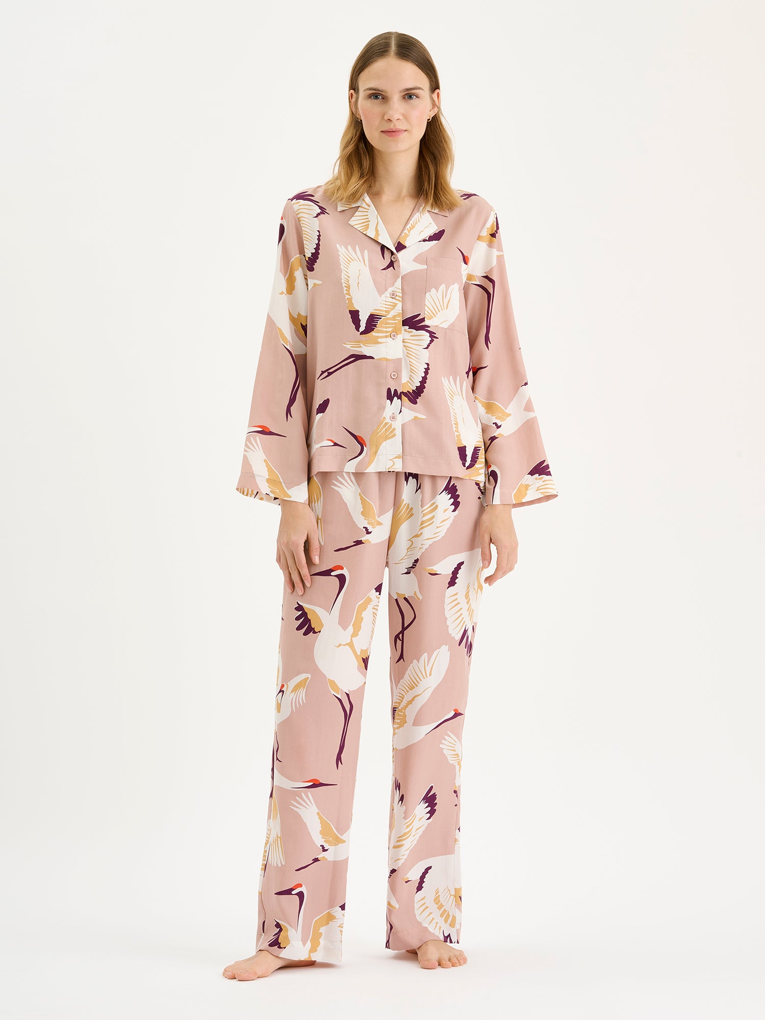 Nanson naisten Kurki-pyjamapaita, jossa on kaunis ja näyttävä vaaleanpunainen kuosi, mallin päällä saman sarjan housujen kanssa.