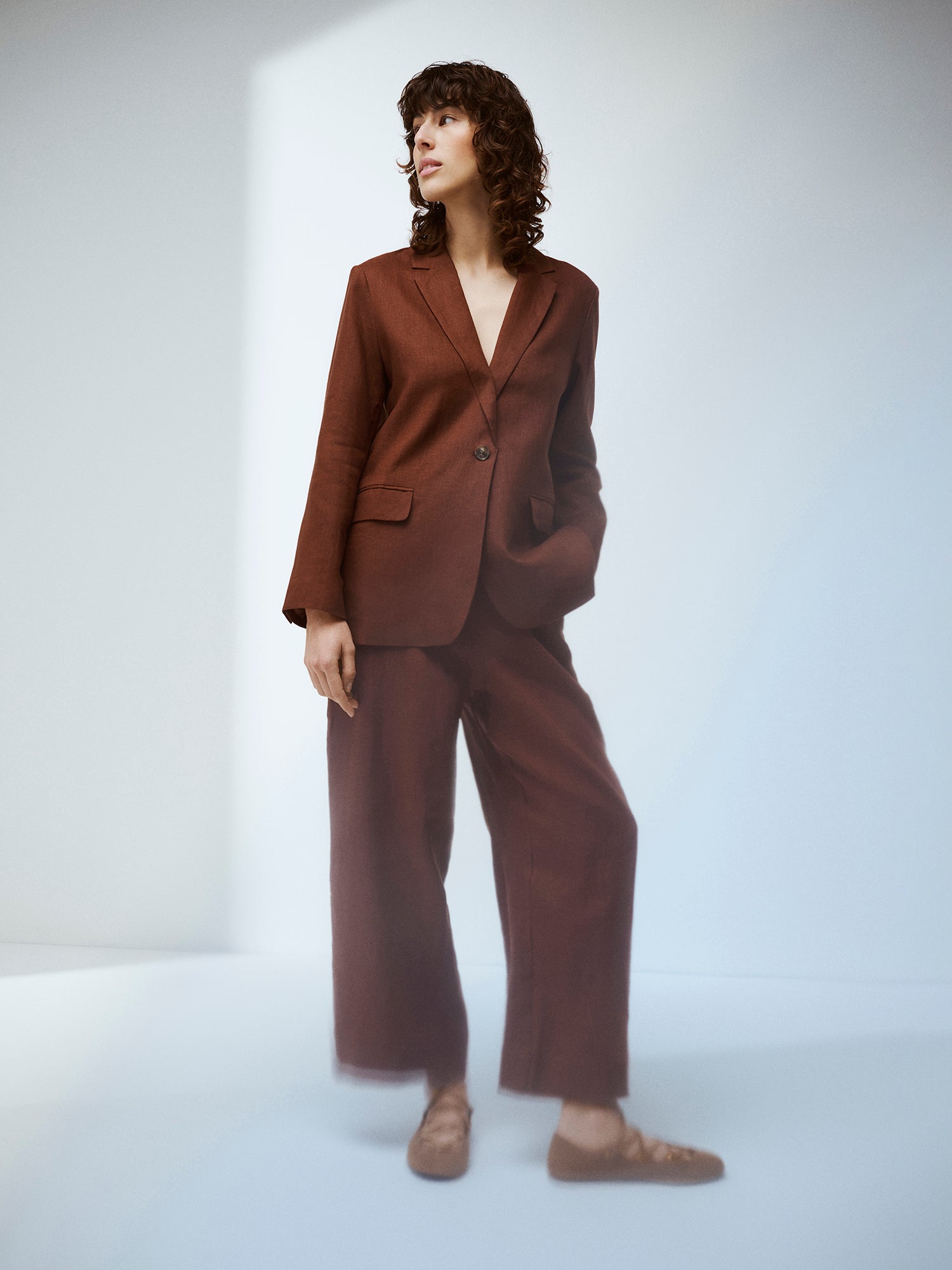 Nanson naisten ruskeat Saari-pellavahousut vajaamittaisilla lahkeilla mallin päällä ruskean pellavableiserin kanssa.