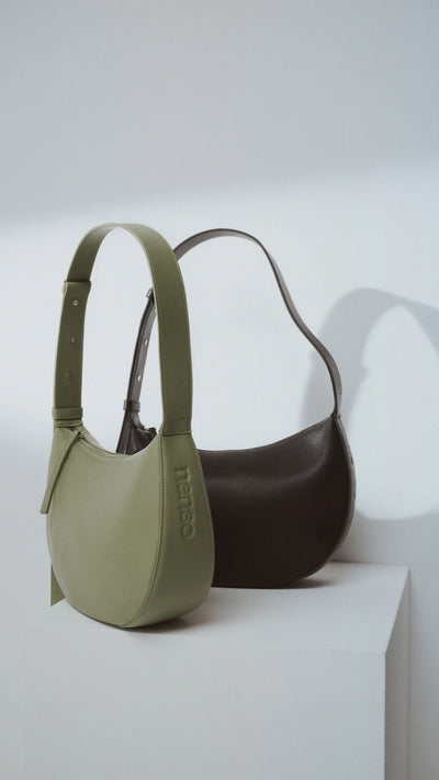 Tyylikäs ja trendikäs puolikuun mallinen musta OLKA KUU - nahkalaukku. Laukussa on olalle sopiva kantohihna ja logo nahan pinnassa. Vuoritetussa laukussa on päällä metallinen vetoketju. Brändikuvassa musta ja vaaleanvihreä OLKA KUU laukku.