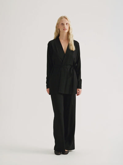 Naisten rennon tyylikkäät Roma-housut trendikkäillä levenevillä lahkeilla mallin päällä Roma jakun kanssa.